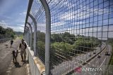 Warga menggiring hewan ternak melintas di jembatan penyeberangan di atas Jalan Tol Cipularang, Padalarang, Kabupaten Bandung Barat, Jawa Barat, Selasa (22/4/2025). PT Jasa Marga (Persero) Tbk (JSMR) akan melakukan penyesuaian tarif di dua ruas tol kelolaannya, yakni Tol Cikampek-Purwakarta-Padalarang (Cipularang) dan Tol Padalarang-Cileunyi (Padaleunyi) yang dijadwalkan berlaku pada Mei 2025. ANTARA FOTO/Abdan Syakura/agr