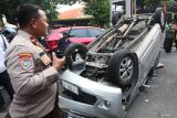 Polisi mengamati kondisi mobil yang terbalik di Jalan Kusuma Bangsa, Surabaya, Jawa Timur, Selasa (22/4/2025). Mobil Toyota Avanza bernomor polisi L 1798 PW yang diduga mengalami pecah ban saat melaju itu terbalik usai menabrak mobil Honda Jazz bernomor polisi L 1344 VU yang terparkir dipinggir jalan dan berhenti setelah menabrak mobil Mazda bernomor polisi L 1152 ABZ, serta tidak ada korban jiwa dalam peristiwa tersebut. ANTARA Jatim/Didik Suhartono/mas.