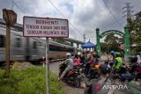 Pengendara sepeda motor menunggu untuk menyeberangi jalur perlintasan kereta api sebidang di Ngamprah, Kabupaten Bandung Barat, Jawa Barat, Kamis (24/4/2025). Menteri Perhubungan Dudy Purwagandhi menegaskan bahwa keselamatan masyarakat di 3.693 titik perlintasan sebidang di seluruh Indonesia menjadi perhatian serius menyusul sejumlah kecelakaan yang terjadi di perlintasan tersebut. ANTARA FOTO/Abdan Syakura/agr