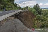 Warga berdiri melihat jalan yang longsor di Desa Neglasari, Kabupaten Ciamis, Jawa Barat, Jumat (25/4/2025). Intensitas curah hujan tinggi di wilayah Kabupaten Ciamis mengakibatkan jalan alternatif yang menghubungkan Ciamis dengan Kabupaten Pangandaran dan Kabupaten Tasikmalaya longsor dan hanya bisa dilalui satu jalur atau buka tutup serta tidak bisa dilewati saat hujan deras. ANTARA FOTO/Adeng Bustomi/agr