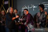 Ketua dewan juri Anugerah Pewarta Foto Indonesia (APFI) 2025 Oscar Motuloh (kiri) menyerahkan piala penghargaan kepada pewarta foto LKBN Antara Muhammad Bagus Khoirunas (tengah) untuk kategori Essay General News saat ajang APFI 2025 di Loji Gandrung, Solo, Jawa Tengah, Jumat (25/4/2025). Ajang APFI 2025 yang digelar organisasi Pewarta Foto Indonesia (PFI) tersebut memberikan tujuh kategori dengan 12 penghargaan atas karya fotografi jurnalistik terbaik sepanjang tahun 2024. ANTARAFOTO/Maulana Surya/Spt/gp
