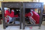 Sejumlah siswa berlindung di bawah meja saat simulasi gempa dan tsunami di SMA Negeri 6  Banda Aceh, Aceh, Sabtu (26/4/2025). Simulasi mandiri yang melibatkan 350 siswa sebagai agenda rutin setiap bulan di sekolah itu guna meningkatkan kewaspadaan dan pengurangan resiko korban jiwa jika terjadi bencana gempa dan tsunami dan sekaligus dalam rangka memperingati Hari Kesiapsiagaan Bencana Nasional . ANTARA FOTO/Ampelsa.