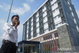 Petugas berjaga dengan latar gedung Asrama Haji Hotel Grand El Hajj di Cipondoh, Kota Tangerang, Banten, Senin (28/4/2025). Asrama Haji tersebut belum bisa melayani keberangkatan jamaah calon haji dan hanya dapat digunakan untuk kepulangan karena masih kurangnya fasilitas pendukung seperti masjid, area parkir serta jalan lingkungan untuk antar barang. ANTARA FOTO/Putra M. Akbar/gp