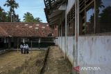 Tiga siswi berjalan di dekat ruang kelas yang rusak di SMP Negeri 2 Cimanuk, Pandeglang, Banten, Senin (28/4/2025). Pihak sekolah menuturkan, sebanyak empat ruang kelas mengalami kerusakan parah dan tiga kelas lainnya rusak ringan sejak sekitar empat tahun terakhir yang mengakibatkan proses belajar mengajar harus dipindahkan ke ruangan lain, serta terpaksa membatasi daya tampung murid karena kekurangan ruang kelas. ANTARA FOTO/Angga Budhiyanto/gp