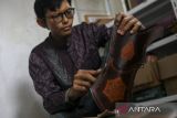 Perajin menyelesaikan pembuatan wadah anak panah atau quiver berbahan dasar kulit di rumah industri Hans Craft, Kota Serang, Banten, Jumat (2/5/2025). Rumah industri tersebut memproduksi beragam kerajinan dari kulit seperti wadah anak panah, dompet, sabuk, serta sampul buku yang dipasarkan ke sejumlah daerah seperti Jakarta, Aceh, Papua hingga memiliki pasar tetap di mancanegara yaitu Amerika Serikat dan Kanada dengan harga Rp65 ribu hingga Rp3 juta. ANTARA FOTO/Angga Budhiyanto/gp
