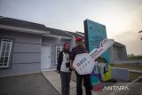 Keluarga pekerja migran berdiri di depan rumahnya usai menerima kunci secara simbolis saat kegiatan kesepakatan kerjasama pembiayaan rumah subsidi di Pegaden, Subang, Jawa Barat, Kamis (8/5/2025). PT Bank Negara Indonesia (Persero) Tbk bekerja sama dengan Kementerian Perumahan dan Kawasan Permukiman (PKP) serta Kementerian Perlindungan Pekerja Migran Indonesia (KP2MI) untuk memberikan solusi pembiayaan rumah bersubsidi bagi 20.000 Pekerja Migran Indonesia (PMI). ANTARA FOTO/Dedhez Anggara/agr