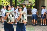 Pelajar membawa makanan bergizi gratis hasil olahan Satuan Pelayanan Pemenuhan Gizi (SPPG) Polda Bali ke dalam kelas di SMP Negeri 3 Denpasar, Bali, Rabu (7/5/2025). SPPG yang saat ini memiliki kapasitas produksi sekitar 3.700 porsi per hari tersebut diluncurkan Polda Bali untuk mendukung peningkatan kualitas generasi muda khususnya dalam aspek kesehatan dan kecukupan gizi. ANTARA FOTO/Fikri Yusuf/wsj.