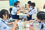 Pelajar menyantap makanan bergizi gratis hasil olahan Satuan Pelayanan Pemenuhan Gizi (SPPG) Polda Bali yang dibagikan di SMP Negeri 3 Denpasar, Bali, Rabu (7/5/2025). SPPG yang saat ini memiliki kapasitas produksi sekitar 3.700 porsi per hari tersebut diluncurkan Polda Bali untuk mendukung peningkatan kualitas generasi muda khususnya dalam aspek kesehatan dan kecukupan gizi. ANTARA FOTO/Fikri Yusuf/wsj.
