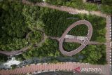Foto udara pengunjung melintasi jembatan saat berwisata di Ketapang Urban Aquaculture, Kabupaten Tangerang, Banten, Senin (12/5/2025). Wisata alam kawasan pesisir seluas 26,9 hektare yang ditanami ribuan pohon mangrove tersebut menjadi salah satu destinasi wisata alternatif dan edukatif bagi masyarakat. ANTARA FOTO/Putra M. Akbar/gp