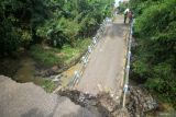 Petugas dari Badan Penanggulangan Bencana Daerah (BPBD) Kabupaten Pasuruan melihat jembatan yang ambrol di Desa Karangjati Anyar, Kecamatan Wonorejo, Pasuruan, Jawa Timur, Selasa (13/5/2025). Jembatan penghubung antarkecamatan tersebut ambrol disebabkan oleh dinding penahan yang tidak mampu menahan pergerakan tanah yang labil akibat intensitas hujan tinggi. Antara Jatim/Umarul Faruq