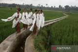 Penari membawakan tarian Napak Jagad di tengah pematang sawah saat pelaksanaan Tradisi Budaya Adat Ngalaksa di Desa Wisata Rancakalong, Sumedang, Jawa Barat, Selasa (13/5/2025). Tradisi dan upacara adat Ngalaksa yang telah diakui sebagai warisan budaya tak benda oleh Kementerian Kebudayaan tersebut merupakan ritual budaya sunda khas Sumedang yang dilakukan sebagai bentuk rasa syukur untuk menyambut musim panen padi yang melimpah. ANTARA FOTO/Novrian Arbi/agr