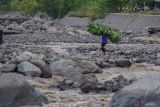 Warga mengangkut pakan ternak siswa  menyeberangi aliran lahar hujan Semeru di Desa Jugosari, Kecamatan Candipuro, Lumajang, Jawa Timur, Kamis (15/5/2025). Sedikitnya 139 KK atau 474 jiwa terisolasi akibat jalur utama dusun tersebut terdampak lahar hujan Gunung Semeru sejak Selasa (13/5). Antara Jatim/Irfan Sumanjaya/um