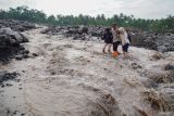 Petugas Kepolisian Polsek Candipuro membantu warga untuk menyeberangi aliran lahar hujan Semeru di Desa Jugosari, Kecamatan Candipuro, Lumajang, Jawa Timur, Kamis (15/5/2025). Sedikitnya 139 KK atau 474 jiwa terisolasi akibat jalur utama dusun tersebut terdampak lahar hujan Gunung Semeru sejak Selasa (13/5). Antara Jatim/Irfan Sumanjaya/um