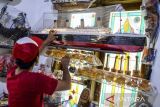 Pekerja menata miniatur kapal Titanic yang terbuat dari limbah stik es krim di rumah produksi WF Craft Miniatur, Kelurahan Tegal Bunder, Kota Cilegon, Banten, Kamis (15/5/2025). UMKM rumahan yang memanfaatkan bahan baku dari limbah seperti kardus bekas, stik es krim, dan kayu untuk dijadikan kerajinan miniatur kapal dan kostum robot bernilai tinggi tersebut dijual dengan harga Rp1-15 juta per buah dan telah dipasarkan hingga luar negeri yaitu di Amerika Serikat dan Peru. ANTARA FOTO/Muhammad Bagus Khoirunas/gp