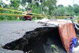 Pengendara melintas di ruas jalan yang rusak (amblas) akibat talud ambrol tergerus banjir / luapan air sungai di Desa Sukorejo, Tulungagung, Jawa Timur, Jumat (16/5/2025). Jalan penghubung antardesa itu sementara ditutup sebagian menggunakan garis polisi, sementara kendaraan dibatasi khusus untuk roda dua, untuk alasan keselamatan dan mengantisipasi longsor susulan. ANTARA Jatim/Destyan Sujarwoko/mas.