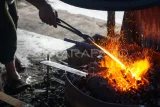 Pandai besi menyelesaikan pembuatan parang secara tradisional di Balikpapan, Kalimantan Timur, Kamis (15/5/2025). Menurut pandai besi yang masih mengandalkan peralatan tradisional tersebut, dalam sehari ia mampu memproduksi sebanyak 10 buah peralatan seperti parang, pisau, kapak, dan sabit yang dijual dengan harga Rp150 ribu hingga Rp600 ribu per buah. Antara Kaltim/Aditya Nugroho/bar/mrh