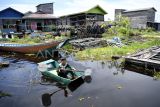 Seorang bocah mendayung saat melintasi Desa Muara Enggelam, Kecamatan Muara Wis, Kabupaten Kutai Kartanegara, Kalimantan Timur, Sabtu (17/5/2025). Desa tanpa daratan yang berada di tengah Danau Melintang tersebut dihuni sekitar 747 jiwa dengan mata pencaharian sebagai nelayan dan menggantungkan hidup pada hasil tangkapan ikan dari sekitar danau, selain itu ada juga warga yang berkebun di ladang terapung atau membuat kerajinan tangan. Antara Kaltim/M Risyal Hidayat