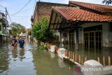 Dua orang anak melintasi banjir yang menggenangi kawasan permukiman di Kampung Bojongasih, Dayeuhkolot, Kabupaten Bandung, Jawa Barat, Jumat (16/5/2025). Hujan yang mengguyur Bandung Raya pada Kamis (15/5) mengakibatkan beberapa kampung di Desa Dayeuhkolot terendam air luapan Sungai Citarum setinggi 40 cm hingga 1 meter. ANTARA FOTO/Raisan Al Farisi/agr