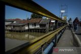 Warga berjalan di dekat permukiman bantaran kali di Kronjo, Kabupaten Tangerang, Banten, Minggu (18/5/2025). Kementerian Sosial menargetkan angka kemiskinan di Indonesia menjadi di bawah lima persen pada tahun 2029 dengan cara menggandeng sejumlah pihak termasuk perguruan tinggi untuk membantu program pengentasan kemiskinan. ANTARA FOTO/Putra M. Akbar/gp