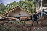 Warga berjalan di depan rumah yang tertimbun material longsor di Desa Wangunsari, Lembang, Kabupaten Bandung Barat, Jawa Barat, Minggu (18/5/2025). Berdasarkan data BPBD Kabupaten Bandung Barat, sebanyak 21 rumah dengan rincian empat rumah rusak berat, satu rumah rusak sedang, satu rumah rusak ringan dan 15 rumah dalam kondisi terancam terdampak bencana longsor akibat tingginya intensitas hujan yang memicu longsor tebing di dekat permukiman warga pada Jumat (16/5). ANTARA FOTO/Abdan Syakura/agr
