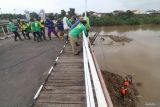 Sejumlah petugas menarik batang bambu dan tumpukan sampah yang tersangkut pada kaki Jembata Lama Kediri (Brug Over Den Brantas te Kediri) di Kota Kediri, Jawa Timur, Selasa (20/5/2025). Pembersihan jembatan cagar budaya berkonstruksi besi pertama di Jawa tersebut dilakukan setelah pladu (flushing atau penggelontoran) bendungan Wlingi dan Lodoyo Blitar yang membawa rumpun bambu bercampur sampah tersangku pada kaki jembatan dan berpotensi merusak konstruksi seiring meningkatnya kembali volume air saat musim hujan. Antara Jatim/Prasetia Fauzani/um