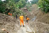 Petugas membersihkan jalur evakuasi, tepat di bawah titik longsor utama di Desa Depok, Trenggalek, Jawa Timur, Rabu (21/5/2025). Operasi SAR gabungan untuk mengevakuasi enam korban longsor yang dilaporkan hilang pada hari kedua di permukiman kaki lereng Gunung Wilis ini masih berfokus pada normalisasi akses jalan untuk mempermudah mobilisasi alat berat, sementara di titik longsor utama pencarian masih dilakukan secara manual karena sulitnya medan dan banyaknya titik longsor yang menutup jalan. ANTARA Jatim/Destyan Sujarwoko/mas.