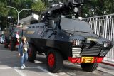 Jurnalis melintas di samping mobil baracuda Brimob Polda Jatim yang disiagakan di depan Stadion Kanjuruhan, Malang, Jawa Timur, Sabtu (24/5/2025). Kepolisian setempat mengerahkan 800 personel untuk mengamankan laga hukuman tanpa penonton antara kesebelasan Arema FC melawan Semen Padang pasca insiden pelemparan bus pemain Persik Kediri oleh oknum suporter yang terjadi saat laga sebelumnya pada Minggu (11/5). ANTARA Jatim/Ari Bowo Sucipto/mas.