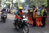 Polisi dan petugas pengaman pertandingan mengawasi pekerja yang melintas di gerbang Stadion Kanjuruhan, Malang, Jawa Timur, Sabtu (24/5/2025). Kepolisian setempat mengerahkan 800 personel untuk mengamankan laga hukuman tanpa penonton antara kesebelasan Arema FC melawan Semen Padang pasca insiden pelemparan bus pemain Persik Kediri oleh oknum suporter yang terjadi saat laga sebelumnya pada Minggu (11/5). ANTARA Jatim/Ari Bowo Sucipto/mas.