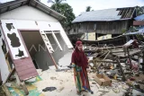 Warga berdiri di depan rumahnya yang rusak akibat tanah amblas di kawasan jalan Poros Samarinda-Balikpapan di Desa Batuah, Loa Janan, Kabupaten Kutai Kartanegara, Kalimantan Timur, Minggu (25/5/2025). Menurut Kepala Desa Batuah bahwa tercatat 21 rumah dari 28 Kepala Keluarga (KK) dengan total 88 jiwa serta sebuah masjid yang terdampak akibat amblasnya jalan nasional sepanjang 80 meter. Antara Kaltim/M Risyal Hidayat
