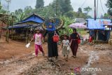 Sejumlah warga penyintas bencana banjir bandang dan longsor berjalan di sekitar hunian sementara (huntara) di Kampung Cigobang, Lebak, Banten, Senin (26/5/2025). Sebanyak 241 kepala keluarga (KK) yang merupakan korban bencana banjir bandang dan longsor pada tahun 2020 tersebut selama lima tahun masih bertahan di tenda huntara dengan akses yang sulit dijangkau dan mengharapkan pemerintah agar segera membangun hunian tetap (huntap) yang telah dijanjikan. ANTARA FOTO/Muhammad Bagus Khoirunas/gp