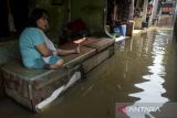Warga duduk di depan teras rumahnya yang terendam banjir di Kampung Candulan, Cipondoh, Kota Tangerang, Banten, Jumat (30/5/2025). Banjir setinggi 30 - 50 cm tersebut akibat luapan Kali Angke yang dipicu tingginya intensitas hujan pada Kamis (29/5) malam. ANTARA FOTO/Putra M. Akbar/gpa
