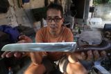 Perajin memperlihatkan pisau yang terbuat dari besi per truk bekas di Kelurahan Rejomulyo, Kota Kediri, Jawa Timur, Kamis (5/6/2025). Berbagai model pisau yang terbuat dari lempengan besi per truk dan mata gerinda bekas tersebut mampu diproduksi hingga 4 buah per hari dan dipasarkan melalui media sosial seharga Rp70 ribu hingga Rp4 juta per buah tergantung kualitas bahan dan ukuran.  ANTARA Jatim/Prasetia Fauzani/mas.