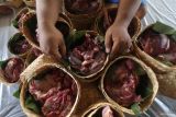Warga menata daging kurban yang dikemas menggunakan anyaman bambu (besek) beralaskan daun jati di Masjid Al-Khalid, Kota Kediri, Jawa Timur, Sabtu (7/6/2025). Pemanfaatan besek dan daun jati sebagai pembungkus daging kurban ramah lingkungan tersebut sebagai upaya mendukung program pemerintah meminimalisir penggunaan plastik. ANTARA Jatim/Prasetia Fauzani/mas.