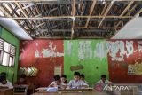 Sejumlah siswa kelas 3 membaca buku usai mengikuti ulangan di SD Negeri Binangun, Kabupaten Serang, Banten, Selasa (10/6/2025). Sebanyak lima ruang kelas di sekolah tersebut mengalami kerusakan dengan kondisi sebagian atap ruang kelas ambruk sejak tahun 2019 sehingga para siswa khawatir saat proses kegiatan belajar mengajar dapat tertimpa atap yang ambruk akibat kayu yang sudah lapuk. ANTARA FOTO/Muhammad Bagus Khoirunas/gp