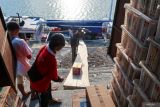 Pekerja memasukan barang ke kapal di Dermaga Pantai Marina Boom, Banyuwangi, Jawa Timur, Rabu (11/6/2025). Kapal tersebut melayani distribusi kebutuhan pokok ke sejumlah kepulauan Madura seperti Pulau Sapeken dan Raas dan sebaliknya kapal itu juga mengangkut hasil bumi dan laut seperti kelapa dan ikan ke Banyuwangi. Antara Jatim/Budi Candra Setya/um
