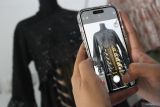 Pelaku usaha fesyen rumahan Febrina Fajarwati memotret busana rancangannnya sebelum diunggah ke media sosial di Gendhis Butik, Ngawi, Jawa Timur, Rabu (11/6/2025). Dalam sebulan pelaku usaha fesyen wastra rumahan tersebut mampu memproduksi sekitar 90 potong busana dengan gaya perkantoran atau office look dengan mengkombinasikan kain batik dan tenun untuk kemudian dijual ke berbagai kota di Indonesia melalui media sosial dengan harga Rp200 ribu hingga Rp1 juta per potong menurut kualitasnya. ANTARA Jatim/Ari Bowo Sucipto/mas.