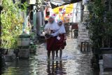 Dua pelajar berjalan melintasi banjir robÂ  yang menggenangi kampung Kalianak Timur, Surabaya, Jawa Timur, Rabu (11/6/2025). Pasang air laut tinggi menyebabkan kampung padat penduduk tersebut tergenang banjir robÂ  dengan ketinggian bervariatif mulai 15 centimeter hingga 25 centimeter tergantung ketinggian permukaan jalan di kampung itu. ANTARA Jatim/Didik Suhartono/mas.