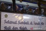 Seorang haji melambaikan tangan dari dalam bus setibanya di Asrama Haji Cipondoh, Kota Tangerang, Banten, Kamis (12/6/2025). Sebanyak 391 jamaah haji asal Tangerang yang tergabung dalam kelompok terbang (kloter) 2 tiba di tanah air setelah melaksanakan ibadah haji di Arab Saudi. ANTARA FOTO/Putra M. Akbar/gp