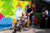 Relawan mendorong kusi roda warga penyandang disabilitas daksa untuk melukis mural di Kampung Binong Jati, Bandung, Jawa Barat, Sabtu (14/6/2025). Kegiatan yang diinisiasi oleh Komunitas Masihan Indonesia tersebut untuk menyalurkan kreativitas perempuan penyandang disabilitas dalam memperindah dan mengenalkan kembali kawasan Binong Jati sebagai sentra rajut yang ada di Kota Bandung sehingga mampu kembali meningkatkan pertumbuhan ekonomi warga. ANTARA FOTO/Novrian Arbi/agr
