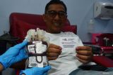 Petugas Palang Merah Indonesia (PMI) memperlihatkan kantong berisi darah dan penderma memperlihatkan kupon pengambilan bingkisan saat kegiatan donor darah dalam rangka Peringatan Hari Donor Darah Sedunia di sekretariat Unit Donor Darah PMI Kota Madiun, Jawa Timur, Sabtu (14/6/2025). Dalam kegiatan tersebut PMI Kota Madiun menyediakan paket bingkisan untuk 100 pendonor pertama berisi beras, minyak goreng, minuman dalam botol dan makanan ringan. Antara Jatim/Siswowidodo/mas.