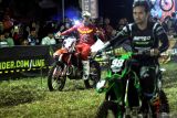 Pebalap  M. Zidane Alnesa (kiri) membagikan suvenir dalam kejuaraan balap motocross dan grasstrack Trial Game Dirt 2025 putaran kedua di sirkuit non permanen Lapangan Graha Tirta Waru, Sidoarjo, Jawa Timur, Sabtu (14/6/2025).  M. Zidane Alnesa berhasil menjuarai dengan nilai total poin 100 di kelas FFA Open disusul Asep Lukman dengan 82 poin dan ketiga Ananda Rigi dengan 78 poin. Antara Jatim/Umarul Faruq