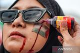 Pengunjuk rasa merias wajahnya dengan tinta merah saat aksi solidaritas global march to Gaza di Jalan Asia Afrika, Bandung, Jawa Barat, Minggu (15/6/2025). Aksi yang diselenggarakan serentak di empat kota di Indonesia yaitu Jakarta, Bandung, Makassar, dan Malang tersebut merupakan bentuk solidaritas untuk gerakan Global March to Gaza yang bertepatan dengan ribuan warga lintas negara dalam persiapan memasuki wilayah Gaza guna memberikan bantuan kepada rakyat Palestina yang mengalami krisis akibat blokade dari Israel. ANTARA FOTO/Raisan Al Farisi/agr