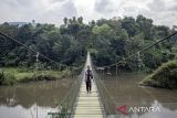 Warga berjalan di atas Jembatan Gantung Citarum di Cihampelas, Kabupaten Bandung Barat, Jawa Barat, Minggu (15/6/2025). Bupati Bandung Barat Jeje Ritchie Ismail menyatakan jembatan gantung yang memiliki panjang sekitar 100 meter dan menghubungkan Desa Pataruman dengan Desa Margaasih tersebut menjadi salah satu potensi ekowisata yang dapat dimanfaatkan serta dikelola oleh Koperasi Desa Merah Putih di wilayah itu. ANTARA FOTO/Abdan Syakura/agr