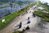 Foto udara pengendara sepeda motor melewati tanggul penahan lumpur Lapindo untuk menghindari banjir di Jalan Raya Porong, Sidoarjo, Jawa Timur, Selasa (17/6/2025). Curah hujan yang tinggi sejak Senin (16/6) malam mengakibatkan banjir yang merendam jalan raya Porong setinggi 50-70 cm sehingga mengganggu kelancaran transportasi umum. Antara Jatim/Umarul Faruq