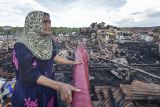 Warga berdiri di samping puing-puing sisa bangunan rumahnya yang terbakar di Sungai Dualap, Tanjung Jabung Barat, Jambi, Selasa (17/6/2025). Pemprov Jambi dan Pemkab Tanjung Jabung Barat menyerahkan bantuan alat tidur, sembako, dan beberapa peralatan sekolah untuk 122 korban kebakaran yang terpaksa mengungsi di rumah keluarga mereka pascakebakaran yang menghanguskan 54 rumah pada Senin (16/6/2025) siang. ANTARA FOTO/Wahdi Septiawan/foc.