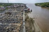Foto udara warga melintas di samping puing-puing sisa bangunan pascakebakaran di Sungai Dualap, Tanjung Jabung Barat, Jambi, Selasa (17/06/2025). Sebanyak 54 rumah di kawasan padat penduduk di pesisir Pantai Timur Jambi tersebut hangus dilalap api pada Senin (16/06/2025) siang yang mengakibatkan 122 jiwa mengungsi. ANTARA FOTO/Wahdi Septiawan/foc.