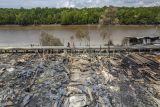 Foto udara warga melintas di samping puing-puing sisa bangunan pascakebakaran di Sungai Dualap, Tanjung Jabung Barat, Jambi, Selasa (17/06/2025). Sebanyak 54 rumah di kawasan padat penduduk di pesisir Pantai Timur Jambi tersebut hangus dilalap api pada Senin (16/06/2025) siang yang mengakibatkan 122 jiwa mengungsi. ANTARA FOTO/Wahdi Septiawan/foc.
