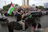 Sejumlah demonstran dari berbagai elemen masyarakat membawa poster, spanduk  dan bendera menggelar aksi long march bela Palestina di Bundaran Simpang Lima, Banda Aceh, Aceh, Minggu (22/6/2025).  Sekitar tiga ribu masyarakat dari berbagai daerah di provinsi Aceh itu turun ke jalan menggelar aksi damai mendesak PBB dan sejumlah negara memberikan kemerdekaan untuk Palestina dari penjajahan zionis  Israel . ANTARA FOTO/Ampelsa.