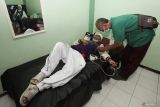 Petugas kesehatan memeriksa kesehatan seorang haji dari kelompok terbang (kloter) 33 setibanya di Asrama Haji Sukolilo Surabaya, Surabaya, Jawa Timur, Minggu (22/6/2025). Sebanyak 376 jamaah haji kloter 33 yang menumpang pesawat Saudi Airlines SV-5688 dengan rute Jeddah Arab Saudi-Surabaya itu telah tiba di Surabaya yang sebelumnya pada Sabtu (21/6/2025) pesawat dengan nomor penerbangan tersebut mendarat darurat di Bandara Internasional Kualanamu, Kabupaten Deli Serdang, Sumatera Utara akibat adanya dugaan teror bom. ANTARA Jatim/Didik Suhartono/mas.