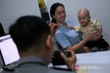 Petugas Kantor Imigrasi Kelas I TPI Pontianak merekam data pemohon anak sebagai bagian dari proses pembuatan paspor di Pontianak, Kalimantan Barat, Selasa (24/6/2025). Kantor Imigrasi Kelas I TPI Pontianak mencatat telah menerbitkan 14.407 buku paspor sepanjang Januari hingga Mei 2025, seiring meningkatnya permintaan dokumen perjalanan untuk keperluan ibadah, wisata, pengobatan, pendidikan dan pekerjaan di luar negeri. ANTARA FOTO/Jessica Wuysang
